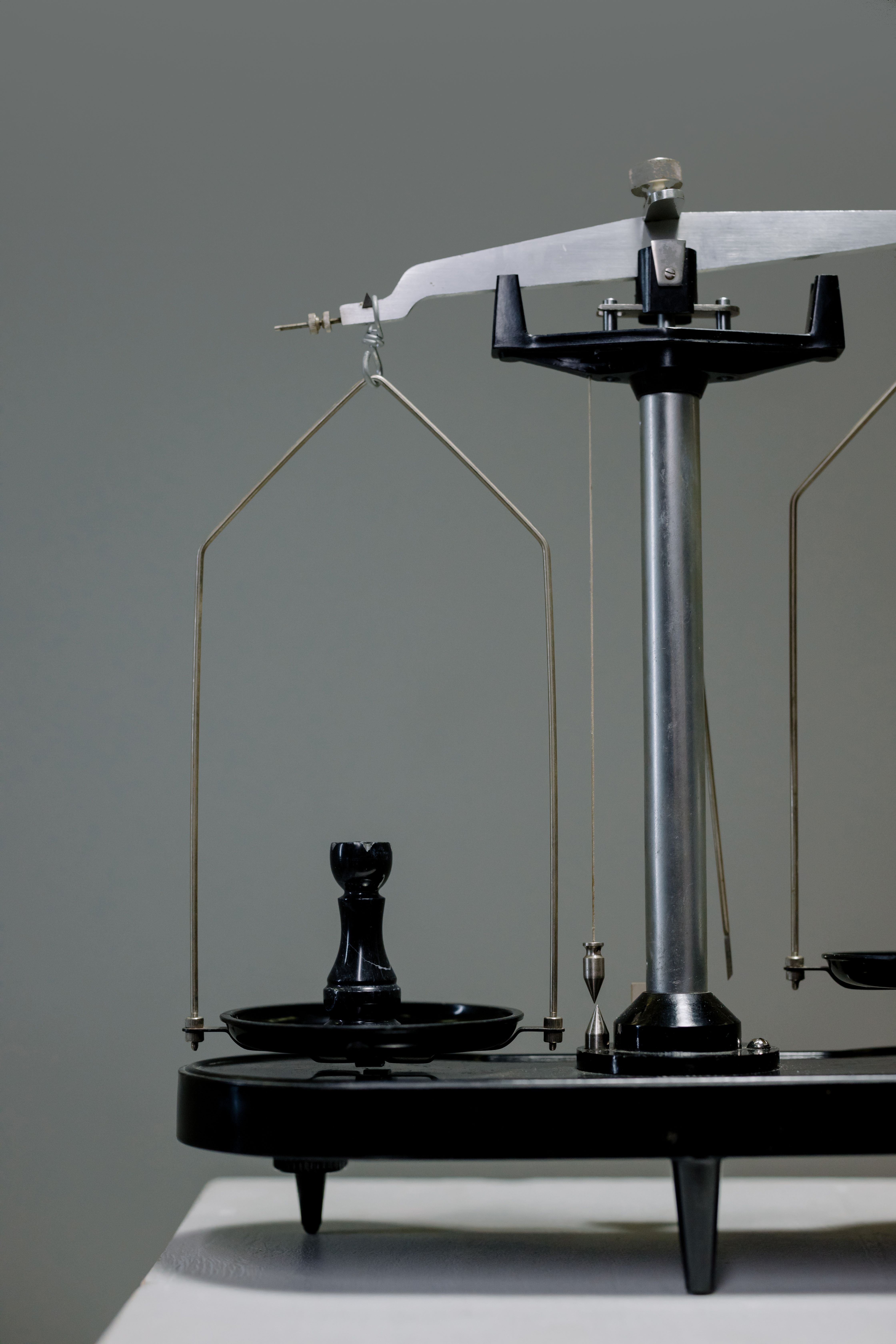 Close-up of a vintage scale with a chess piece balancing conceptually.